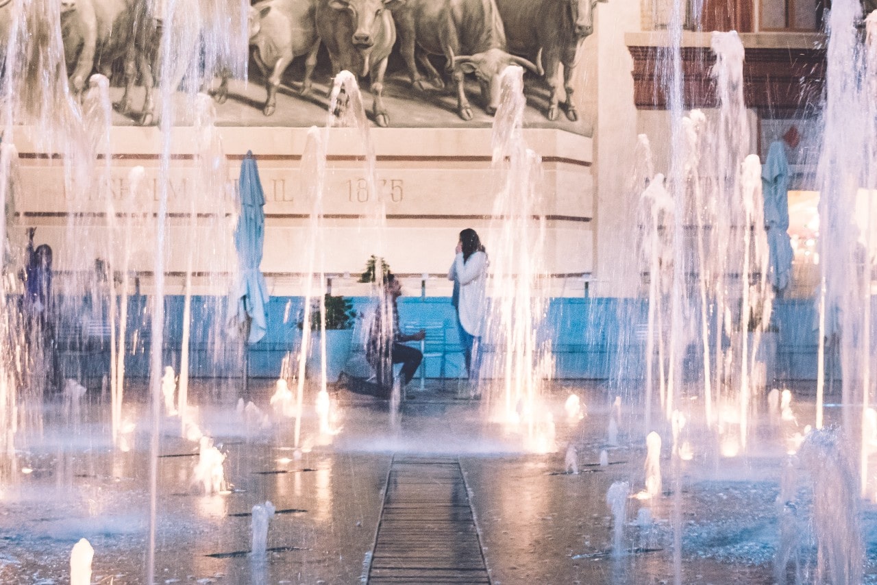couple proposing in front of water fountain