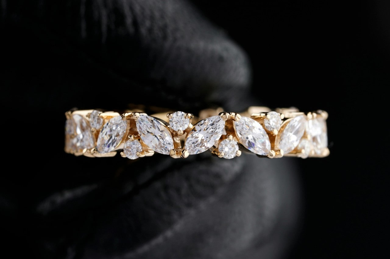 close up image of a yellow gold wedding band with marquise and round cut diamonds
