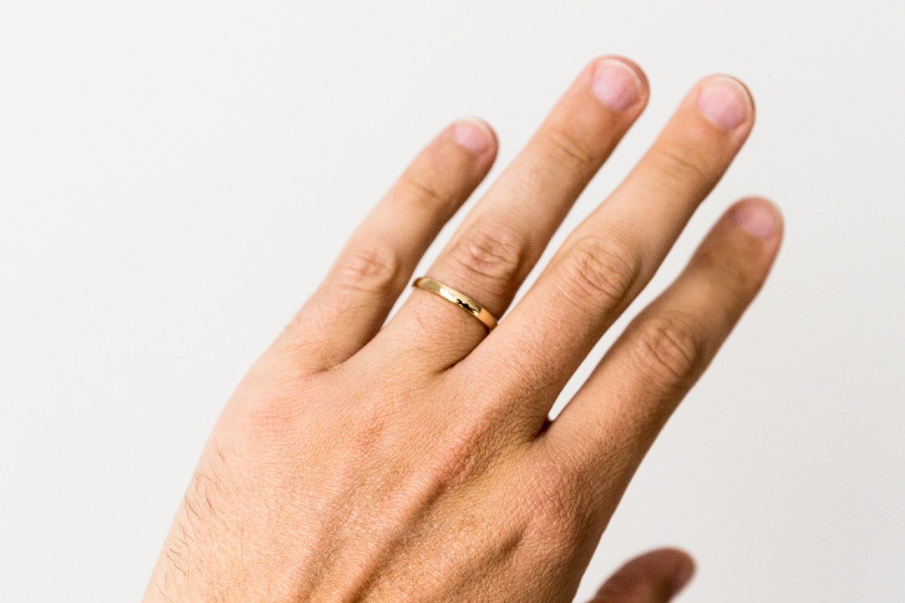 a man’s hand wearing a simple gold wedding band
