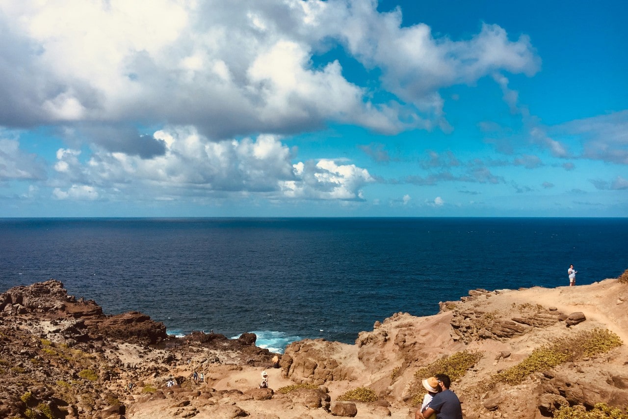 a couple embracing and overlooking the ocean from a rocky cliff in Hawaii