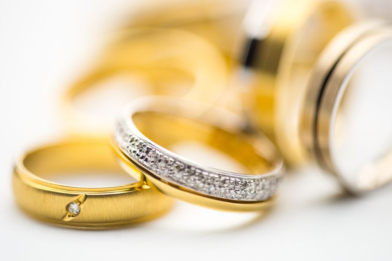 A close-up of a small selection of gold wedding bands, with a diamond accented ring front and center.