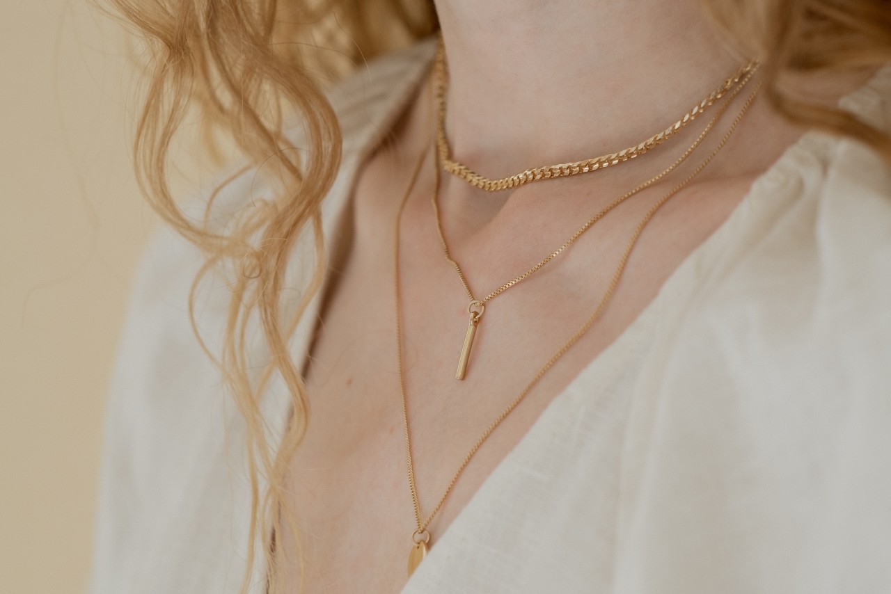 a woman wearing three layered yellow gold necklaces a woman wearing three layered yellow gold necklaces