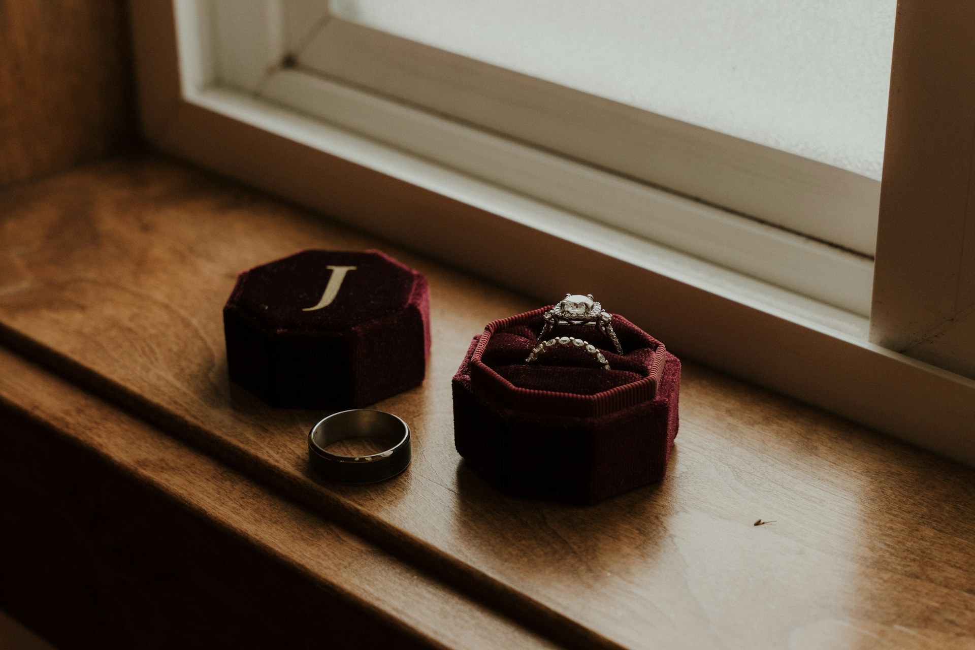 a black wedding band sitting on a windowsill next to other bridal rings a black wedding band sitting on a windowsill next to other bridal rings