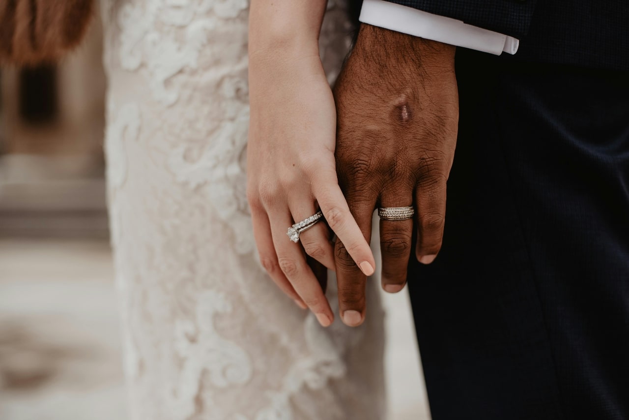 A bride and groom holding hands, the bride wearing a white gold engagement ring. A bride and groom holding hands, the bride wearing a white gold engagement ring.