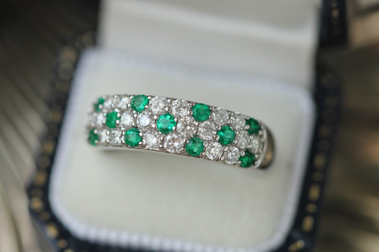 a diamond and emerald pave set wedding band in a ring box a diamond and emerald pave set wedding band in a ring box